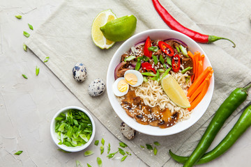 Noodles with beef meat, chili peppers and mushrooms in bowl on grey stone background. Asian Cuisine Pasta. Top view. 