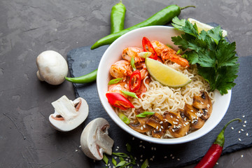 Noodles with shrimp, chili peppers and mushrooms in bowl on dark stone background. Asian Cuisine Pasta.  