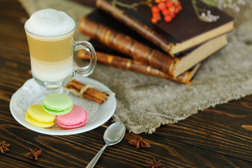 latte and macaroons close-up on a wooden background on a background of old books and burlap