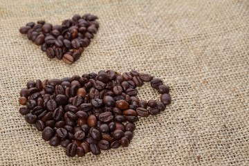 Roasted coffee beans placed in the shape of a cup and placed on sackclothe