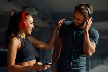 Young sports couple listening to music and laughing
