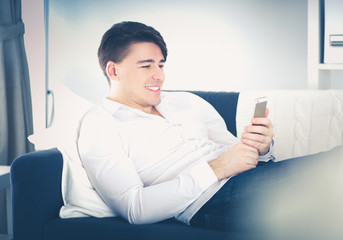Handsome young man using smartphone at home