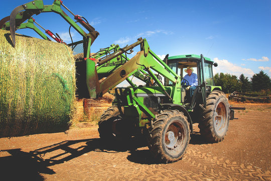 Elderly Farmer Working On Farm With Tractor