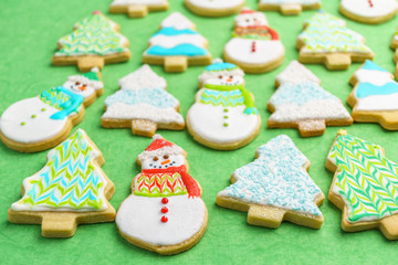 Christmas snowman and tree cookies on green background.