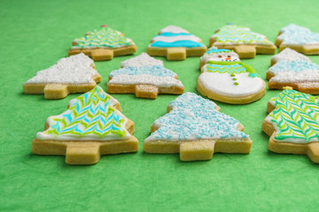 Christmas snowman and tree cookies on green background.