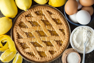 Delicious lemon pie with cooking ingredients on the wooden table 