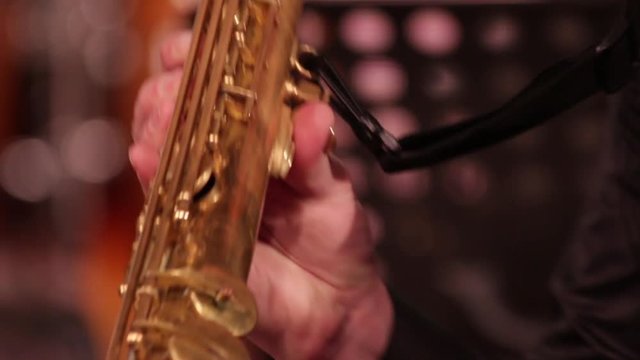 Playing on a wooden wind instrument soprano saxophone. Close-up. The musician retrieves the sounds of music by clamping the keys and ends the game.