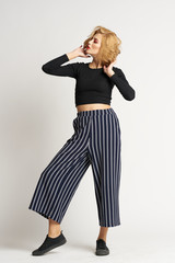 blonde in striped pants posing on light background