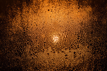 Drops of water on a foggy window in the light of a street lamp close-up macro abstraction background. Drops of water on a foggy window in the light from the car's headlight.