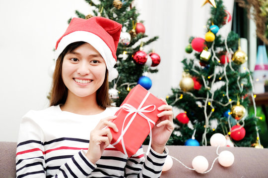 Young cute asian woman smiling and holding red gift box at Christmas party, Christmas people celebration concept