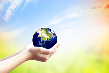 Corporate social responsibility (CSR) concept: Human hands holding globe over blurred abstract nature background. Elements of this image furnished by NASA.