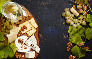 Obraz na płótnie Canvas White Dry Wine, Cheese With Mold, Nuts, Grape And Cracker, Dark Background, Top View