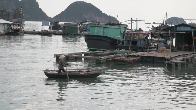 Man rows boats in floating village, Vietnam