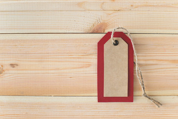 Recycled craft paper red tag and rope on vintage wooden table background with free copy space. Top view. Mock up sample.