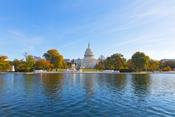 Capitol Hill panorama with reflection pool in late autumn, Washington DC, USA. US Capitol in fall on a cold sunny morning with colorful deciduous trees in its front.