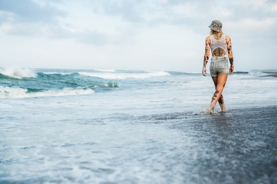 Tattooed woman walking at beach