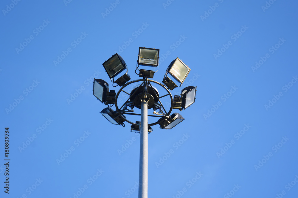 Wall mural spotlight close up of high voltage spotlight tower with blue sky background.