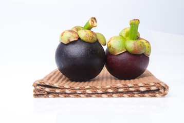 Mangosteen fruit and cross section showing the thick purple skin and white flesh of the queen of fruits.
