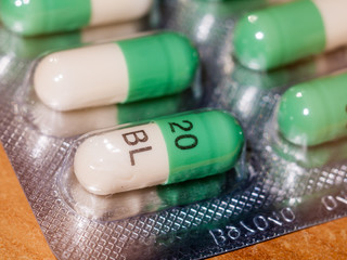 close up detail of foil packet of green and white prozac painkiller tablets on table surface