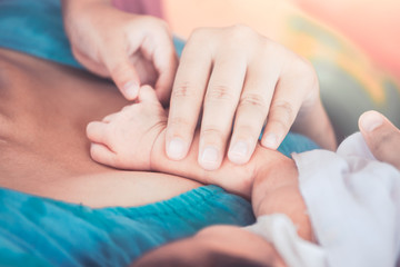 Child and mother holding tiny newborn baby hand with love