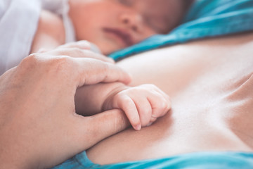 Fototapeta na wymiar Mother hand holding asian newborn baby girl hand while she sleeping with love