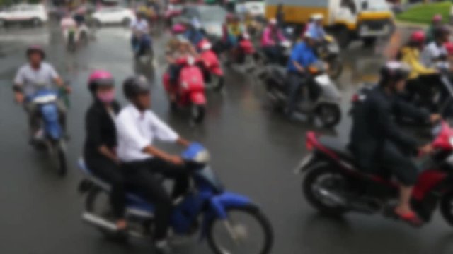 Soft focus, people ride scooters in city