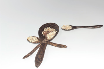 Grains in a wooden spoon on a white background.