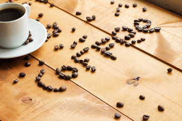 Coffee cup and coffee beans on wooden table .
