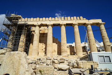 Fototapeta premium Restoration work in progress at world heritage classical Parthenon on marble block base on top of Acropolis with site office, scaffolding and blue sky background