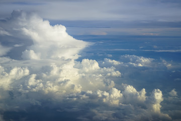 View of abstract dense soft fluffy white cloud copyspace with shades of blue sky and earth background from above flying airplane window in morning sunrise