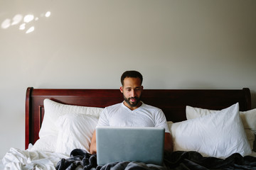 Black man working in bed with laptop computer