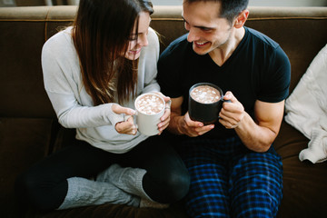 Couple sitting on the couch cuddling and drinking hot chocolate