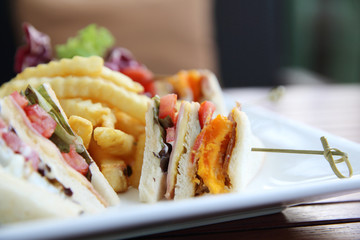 Club sandwich with chicken breast , bacon , tomato , cucumber and fried potatoes