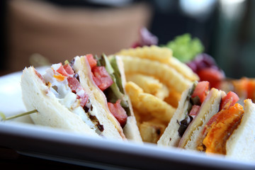 Club sandwich with chicken breast , bacon , tomato , cucumber and fried potatoes