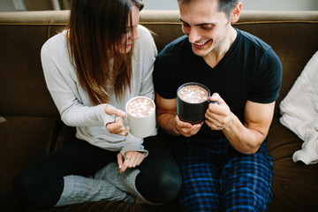 Couple sitting on the couch cuddling and drinking hot chocolate