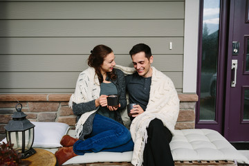 Couple in love sitting on front porch drinking coffee