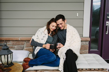 Couple in love sitting on front porch drinking coffee