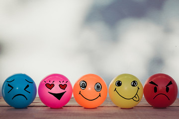 Smiley balls and Emotion balls on wooden table with bokeh wall background and copy space