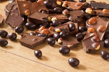 Dark and milk chocolate with hazelnut, round chocolate chip cookies and chocolate dragee on a wooden background