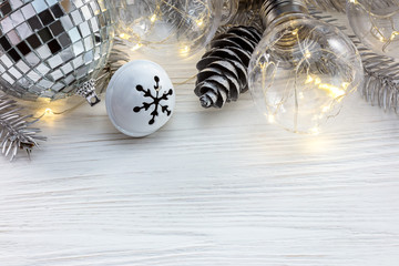 silver christmas tree branch with decorations and retro lamps on white wooden table