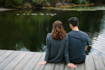 couple sitting on the pier at the lake
