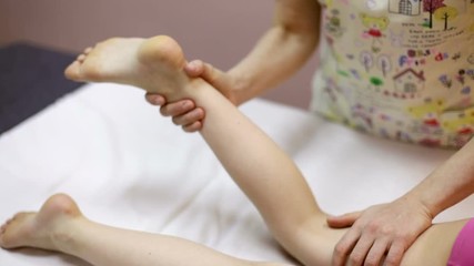 Elementary age girl's leg being manipulated by osteopathic manual therapist - Powered by Adobe