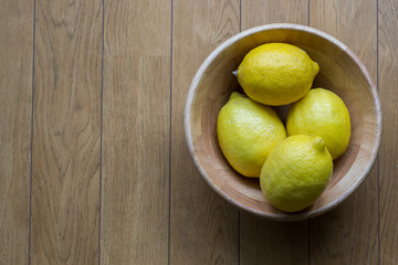 Lemons in a wooden cup on wood table background