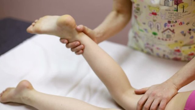 Elementary age girl's leg being manipulated by osteopathic manual therapist