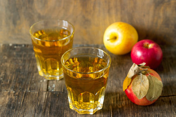 Apple juice in glasses and fresh apples on a wooden background. Rustic style.