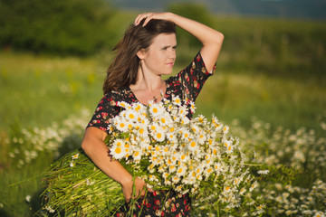 Charming adorable young lady woman dark brunette hairs and green eyes tender sexy posing with flowers wreath on head top and huge bouquet of wild daisy chamomile wearing stylish dress.
