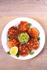 Salmon patties or cakes, lime and avocado on white plate. Fritters of fish. Salmon burgers. Healthy snack or take-away lunch bites, overhead