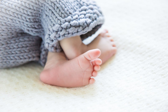 Feet newborn baby in white fur. Selective focus