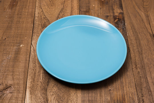 Blue Plate on brown wooden background side view
