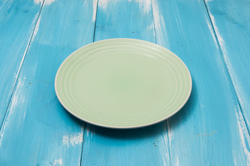 Green Round plate on blue wooden table with perspective